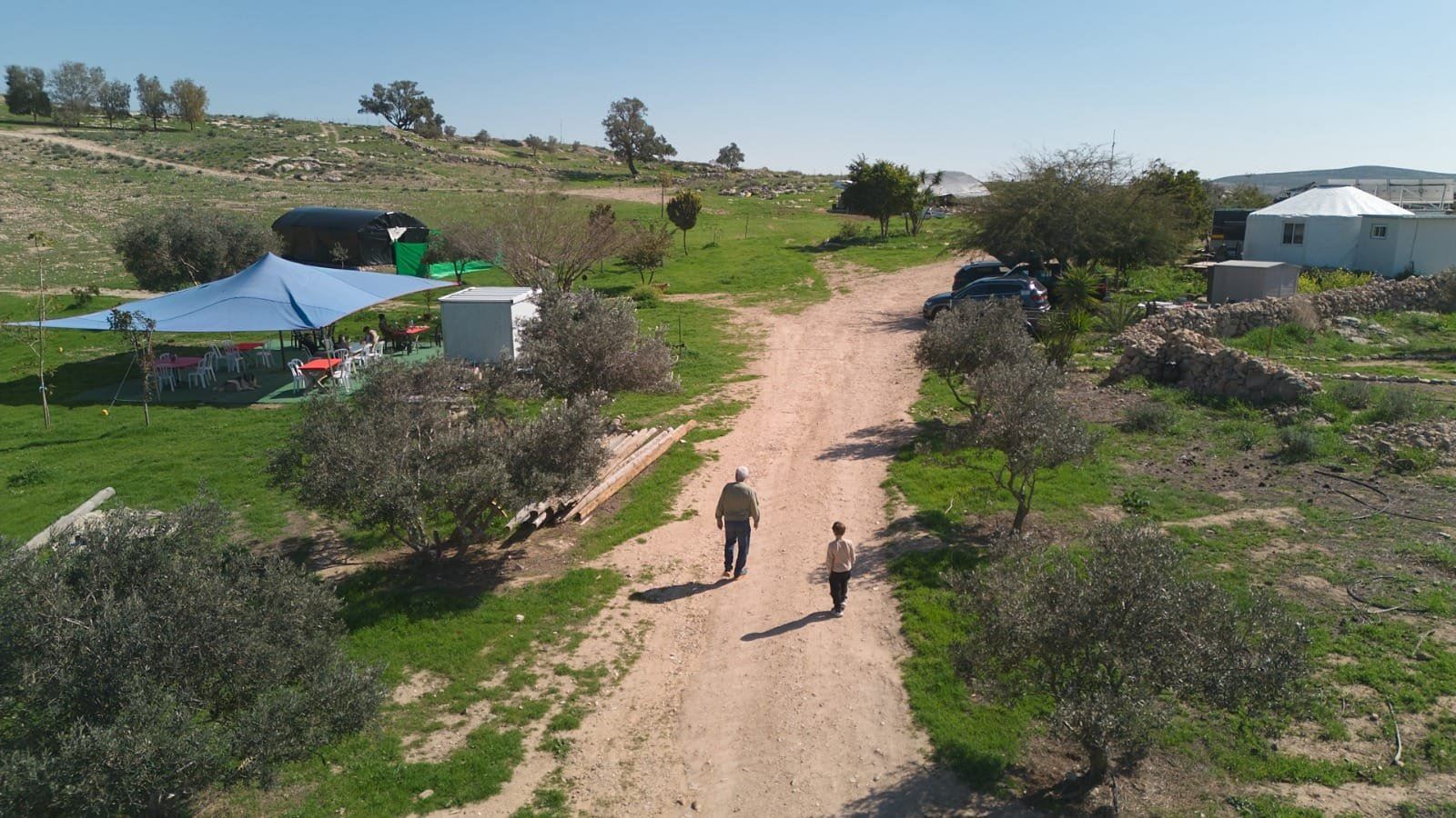 שני מטיילים הולכים בדרך העפר של החווה